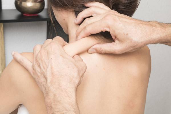 Kvinnlig patient som får medicinsk massageterapi i axeln på en klinik i Halmstad.